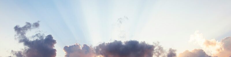 man raising his arms on sea under black clouds