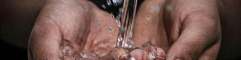 pouring water on person's hands