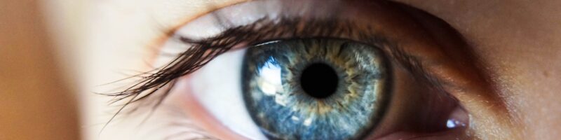 person opening his right eye with blue iris