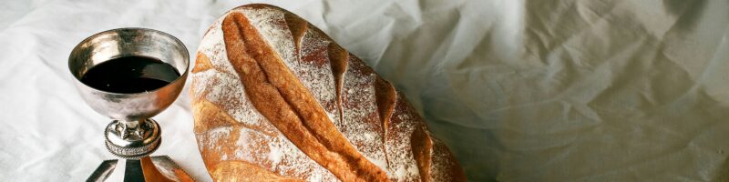 bread on white textile beside clear glass mug