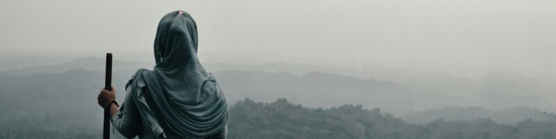 a man with a headscarf and a headscarf holding a gun in a foggy