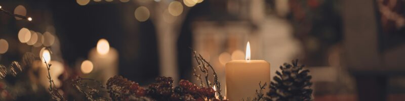 lighted candles on table with pine cones and pine cones