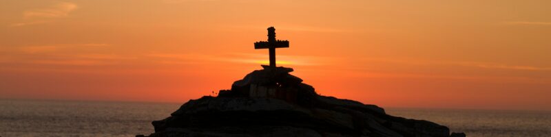 cross silhouette on mountain during golden hour