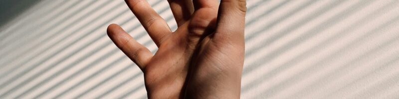 persons left hand on white window blinds