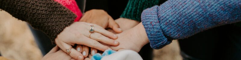group stacking hands in colorful sweaters
