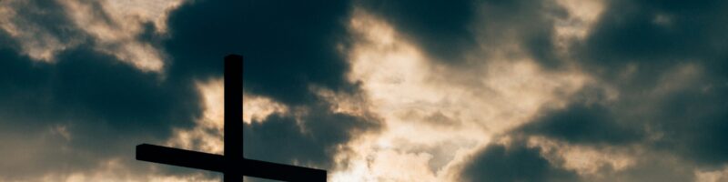 silhouette of cross under cloudy sky